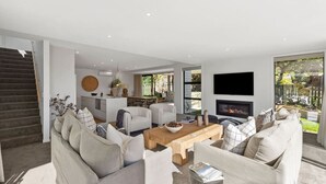 Un salon moderne avec un ensemble canapé, une table basse en bois et un téléviseur à écran plat fixé au mur.