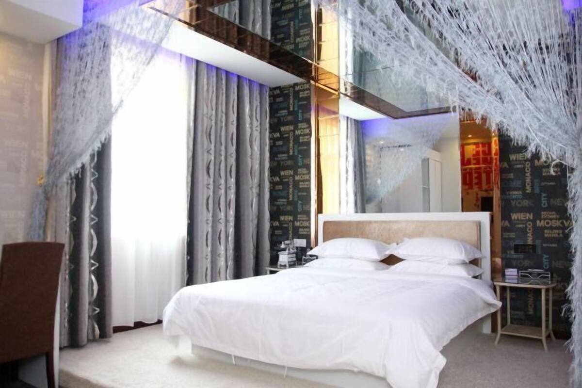 Ein modernes Hotelzimmer mit einem großen Bett, Vorhängen und einer Wand mit Text.
