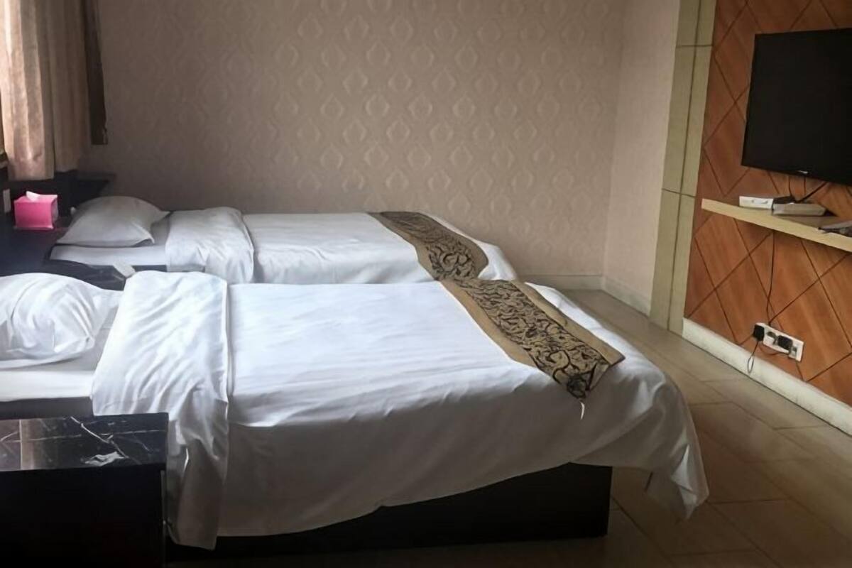 Ein Hotelzimmer mit zwei Betten, einem Fernseher und einem Schreibtisch.