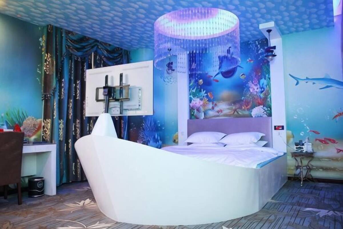 Ein Schlafzimmer mit einem Bett, einem Schreibtisch und einer Aquariumwand.