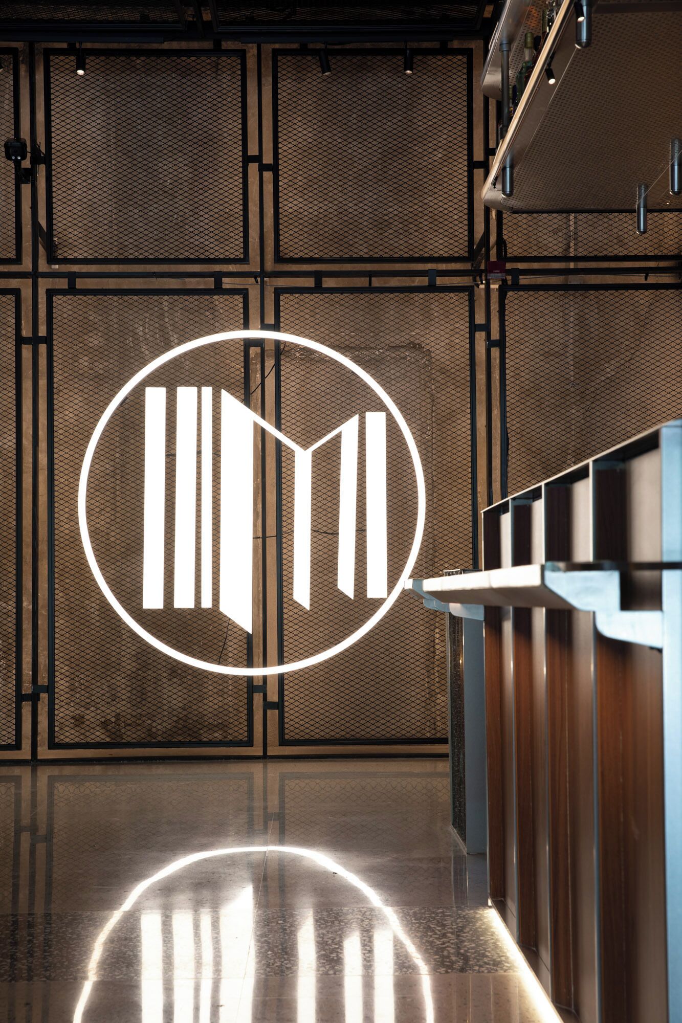 Un área de recepción con diseño moderno, que presenta un logotipo destacado en la pared y un mostrador elegante.