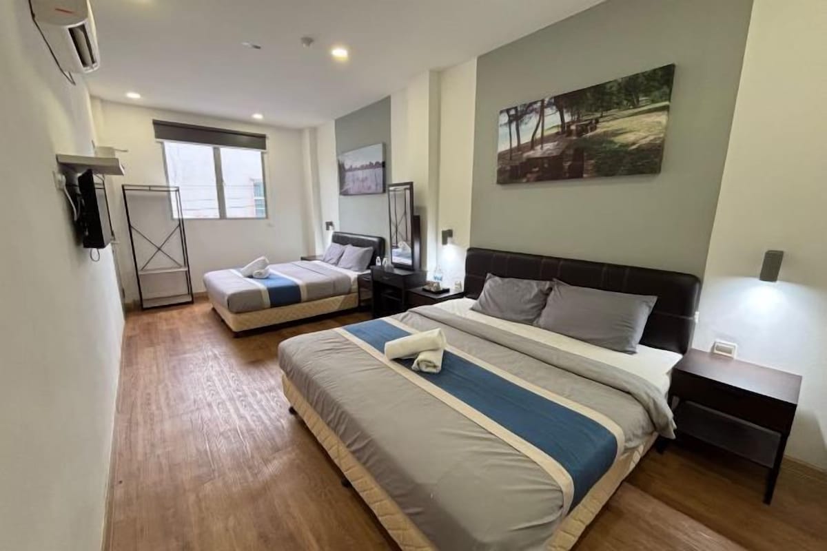 Une chambre d’hôtel avec deux lits, un bureau, une chaise, une lampe et une fenêtre.