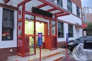 A building with a red-framed entrance, glass doors, and a sign indicating a business or service area.