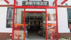 A hotel entrance with a red frame and glass doors, featuring a sign with Chinese characters.