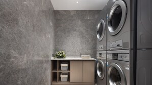 A laundry room with a built-in washer and dryer, a small sink, and storage cabinets. - Wanda Yue Nantong (Nantong)