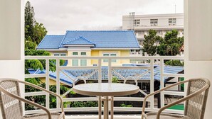 A balcony with a table and two chairs, overlooking a residential area with blue-roofed houses. - New reno, 2 bed townhouse, best location, Patong (Pa Tong)