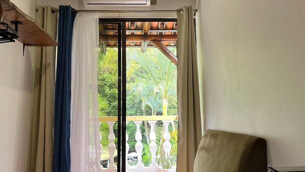 A room with a sofa, a coffee machine, and an air conditioner. There is a balcony with a view of greenery. - Hotel el Páramo (Paramo)