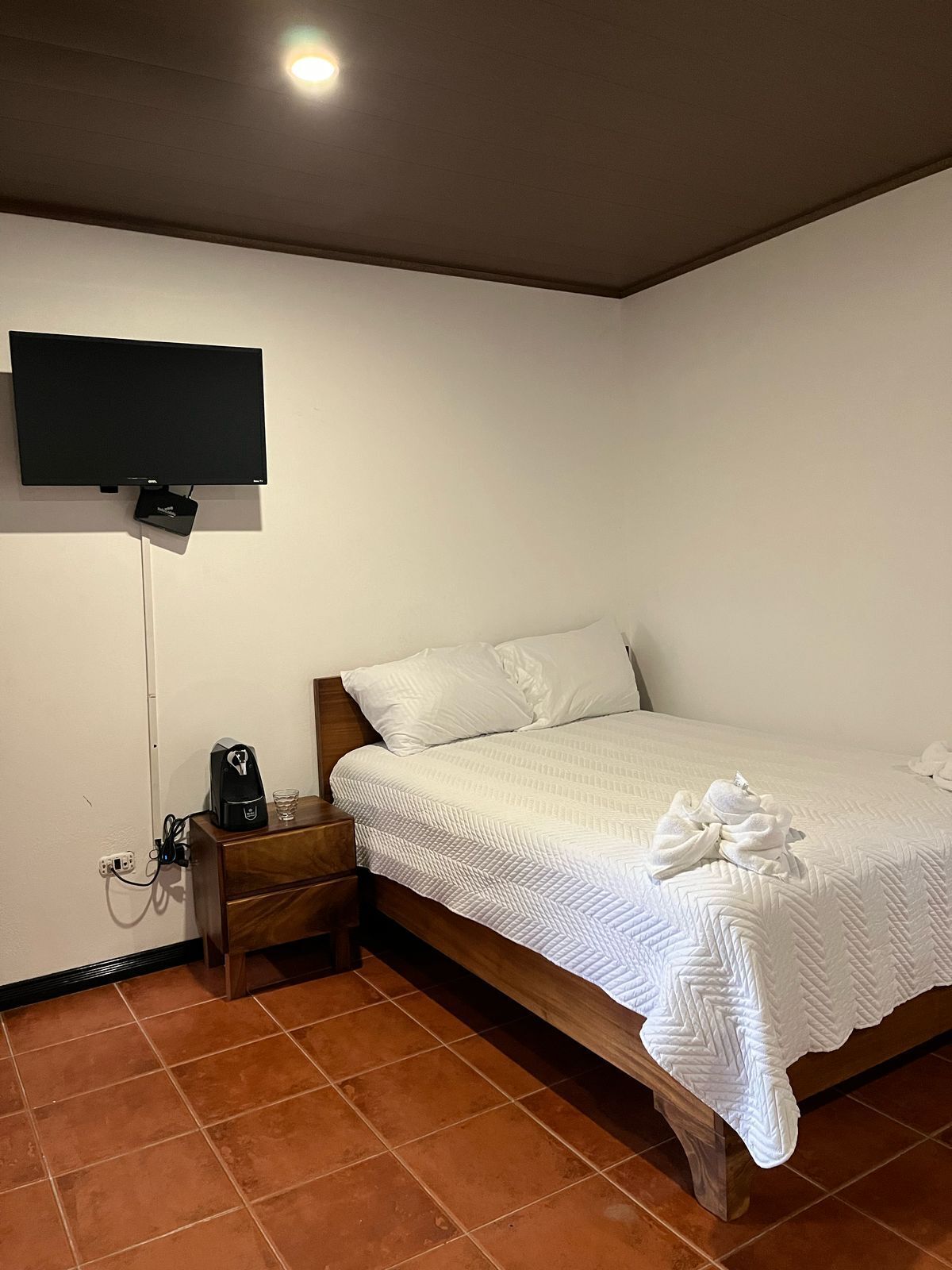 Una camera da letto con un letto, un comodino, una TV a muro e una presa di corrente.