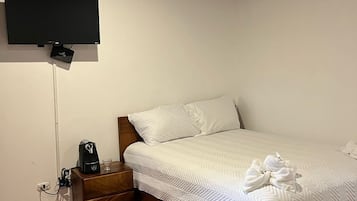 Une chambre à coucher comprenant un lit, une table de chevet, un téléviseur fixé au mur et une prise de courant.