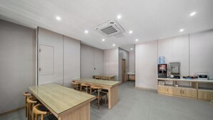 A classroom with wooden tables and chairs, a whiteboard, and a water dispenser. - Hangzhou Melas Hotel (Hangzhou)
