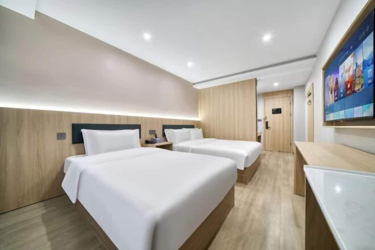 Une chambre d’hôtel avec deux lits, un bureau et un grand écran de télévision.