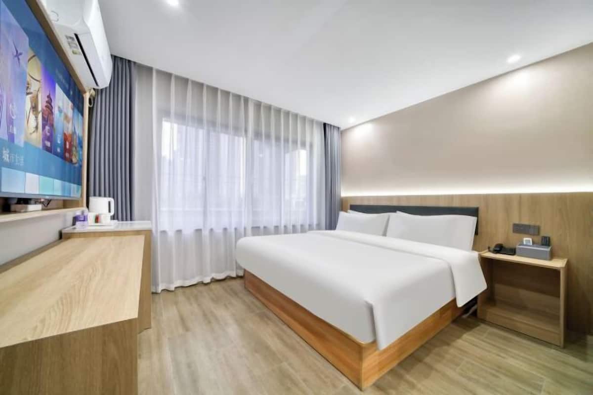 Une chambre d’hôtel avec un lit, une table de chevet, une télévision et des rideaux.
