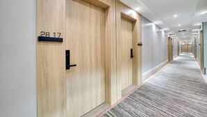 A hotel corridor with wooden doors, numbered room signs, and a carpeted floor. - Hangzhou Melas Hotel (Hangzhou)