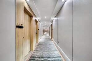 A hotel hallway with wooden doors, a carpeted floor, and a sign indicating room number 28.