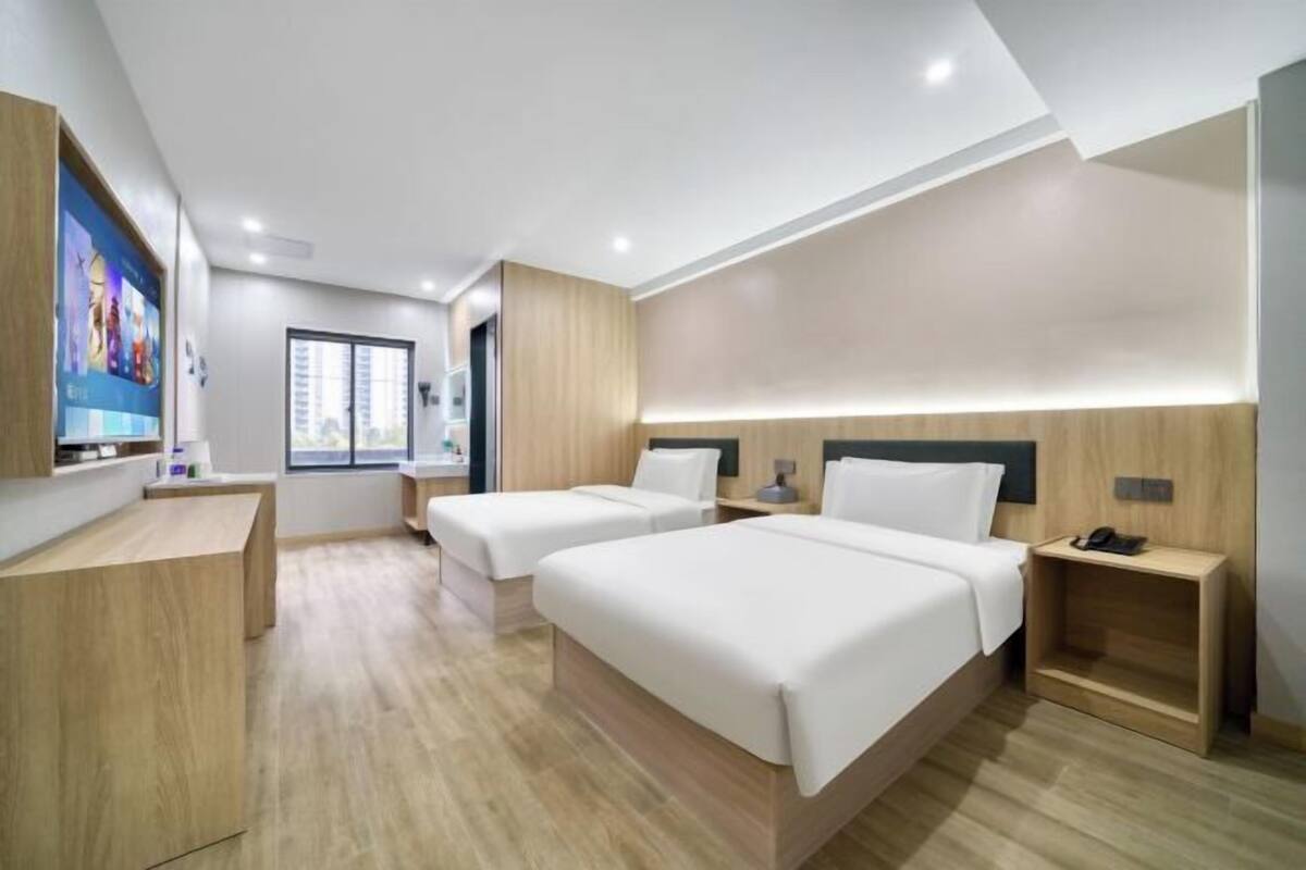 Une chambre d’hôtel moderne avec deux lits, un bureau et une grande fenêtre.
