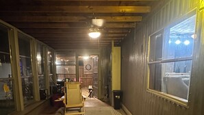 Un couloir avec un plancher en bois, un tapis à motifs, un jeu de fléchettes et un miroir au mur.