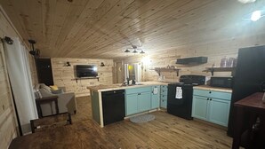 Une cuisine chaleureuse, aménagée dans le style d’un chalet, avec des murs en bois, un îlot central et un coin repas.