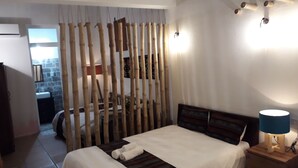 Ein Schlafzimmer mit zwei Betten, einem Holz-Kopfteil, einem Nachttisch mit Lampe und einer Bambus-Raumtrennung.