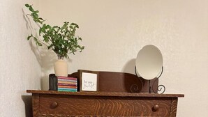 Un armari de fusta amb cinc calaixos, un mirall i una petita planta en test.