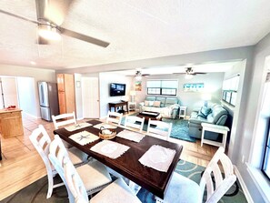 A spacious living area with a dining table, chairs, a sofa, and a TV. - Spacious & Clean, Firepit, Grill, EV Charger, 3min to Beach, Dogs OK Fenced yard (St. Augustine)