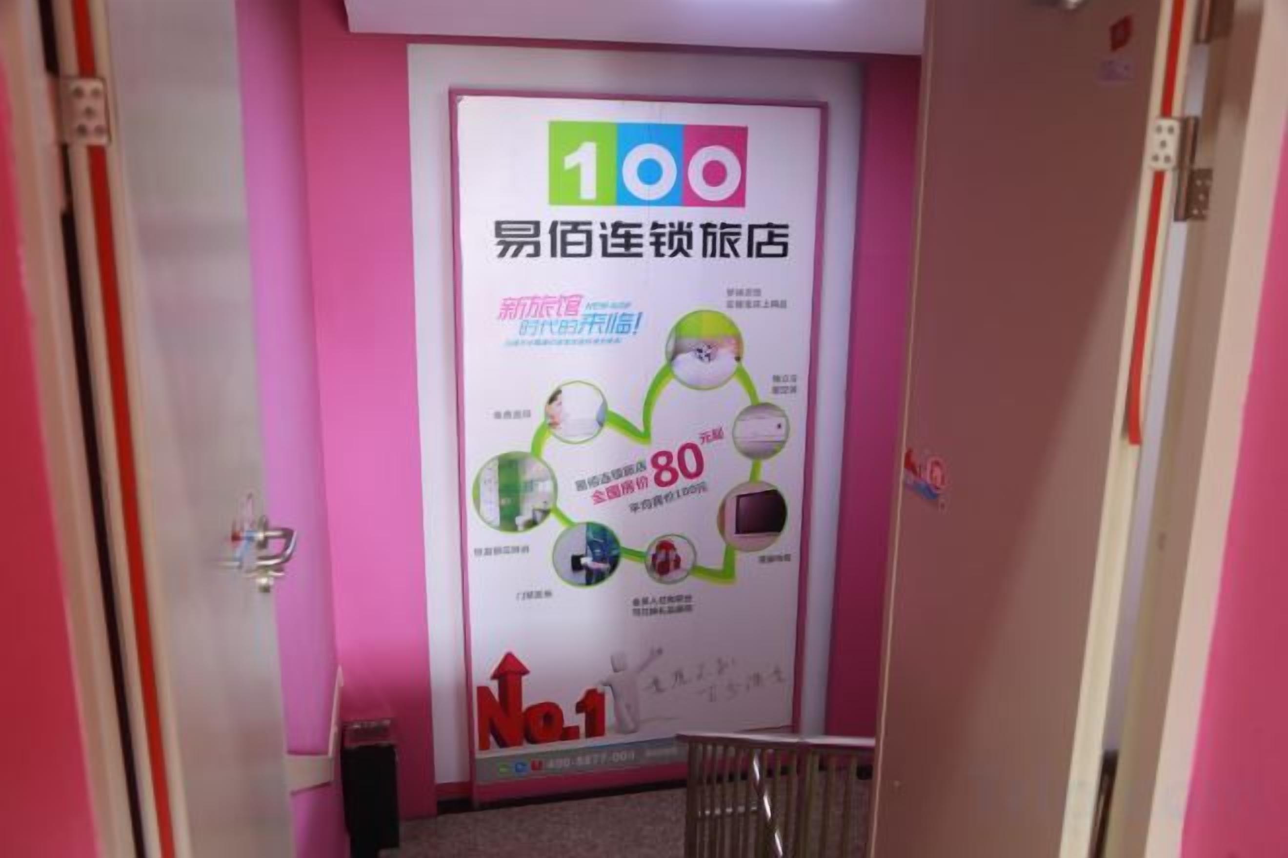 A hallway with a pink wall and a poster advertising a hotel with a 100 rating.