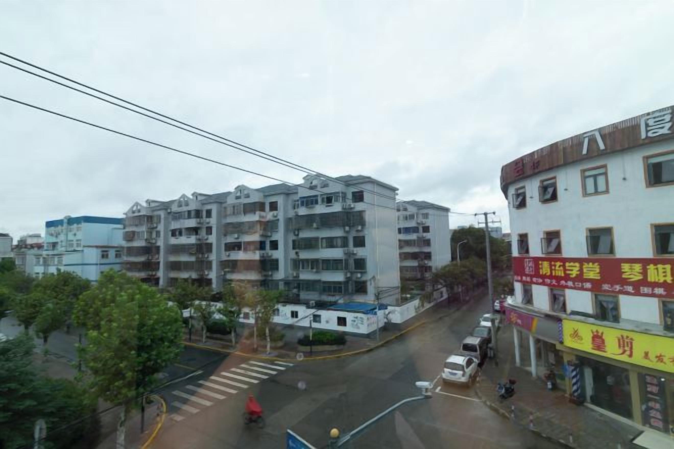 A multi-story building with a commercial ground floor, a pedestrian crossing, and a wet street.