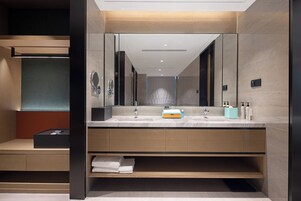 Un baño moderno con un espejo grande, dos lavamanos y estantes empotrados para artículos de aseo.