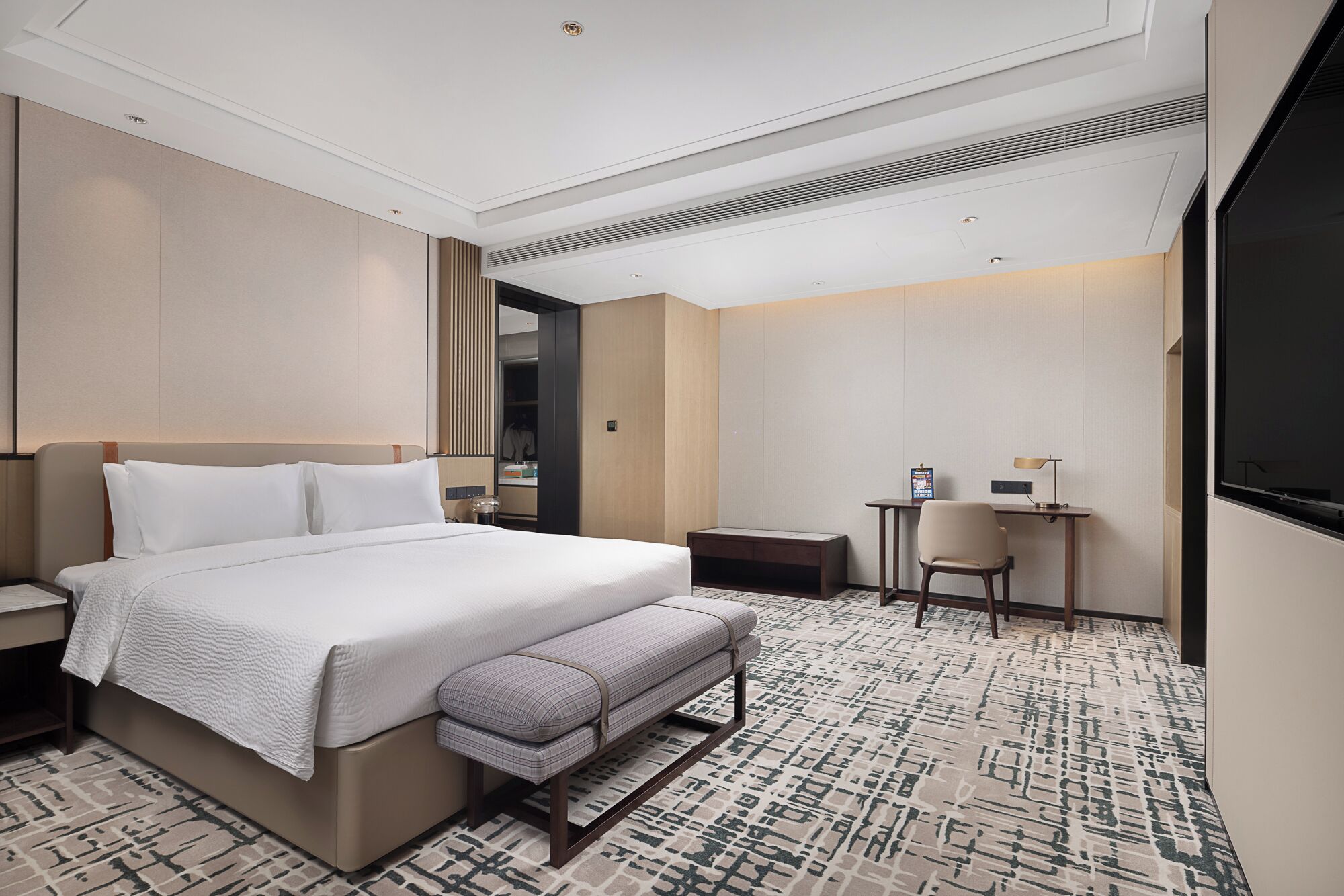 Une chambre d’hôtel moderne, dotée d’un grand lit, d’un bureau et d’une chaise.