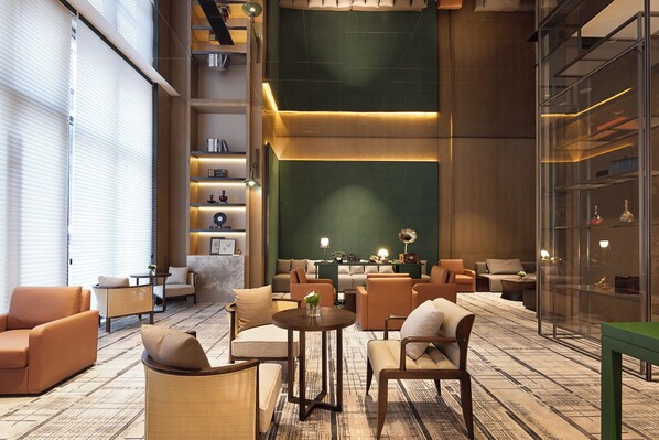 A modern lounge area with comfortable seating, a central table, and a green accent wall. - Wanda Yi Wuhan (Wuhan)