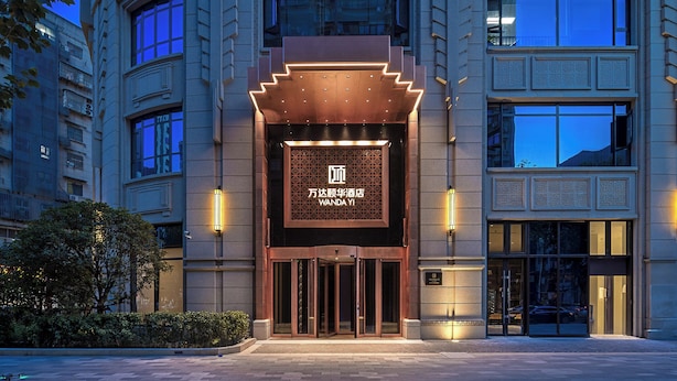 L’extérieur de l’hôtel Wanda Yi se distingue par son entrée imposante, ses grandes fenêtres et ses éléments architecturaux traditionnels.