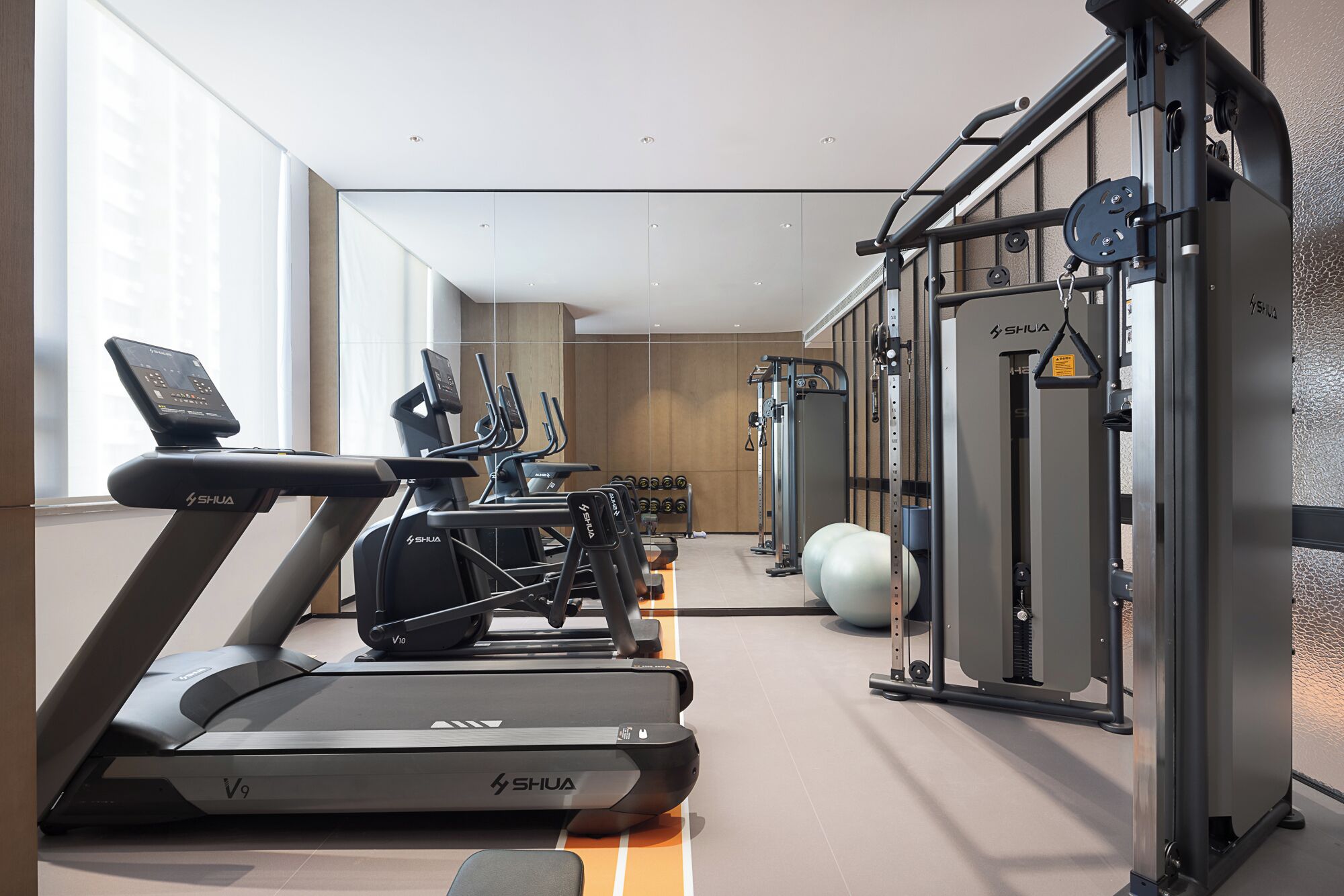 Un gimnasio moderno con cintas de correr, elípticas y equipo de levantamiento de pesas.