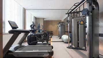 Un gimnasio moderno con cintas de correr, elípticas y equipo de levantamiento de pesas.