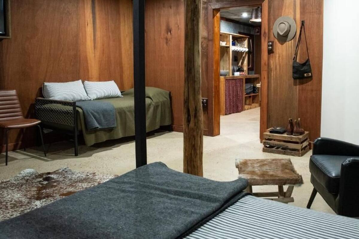 Una habitación con cama, una silla, una mesita y un armario.