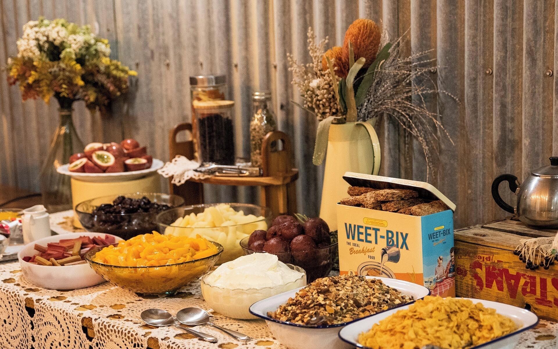 A breakfast table with various food items, a box of Weet-Bix, and a kettle.