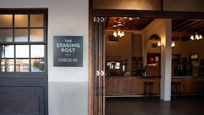 A bar area with a check-in sign, wooden furniture, and a chandelier. - The Staging Post (Longreach)