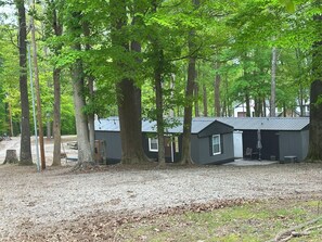Une cabane avec une allée en gravier, entourée de grands arbres.