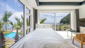 Ein Schlafzimmer mit einem großen Bett, einem Fernseher und Blick auf einen Pool und Berge.