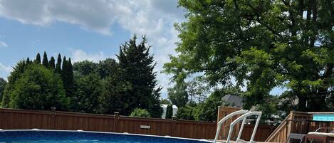A rectangular swimming pool with a wooden deck and a white ladder.