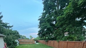 A backyard with a patio area, a wooden fence, and potted plants.