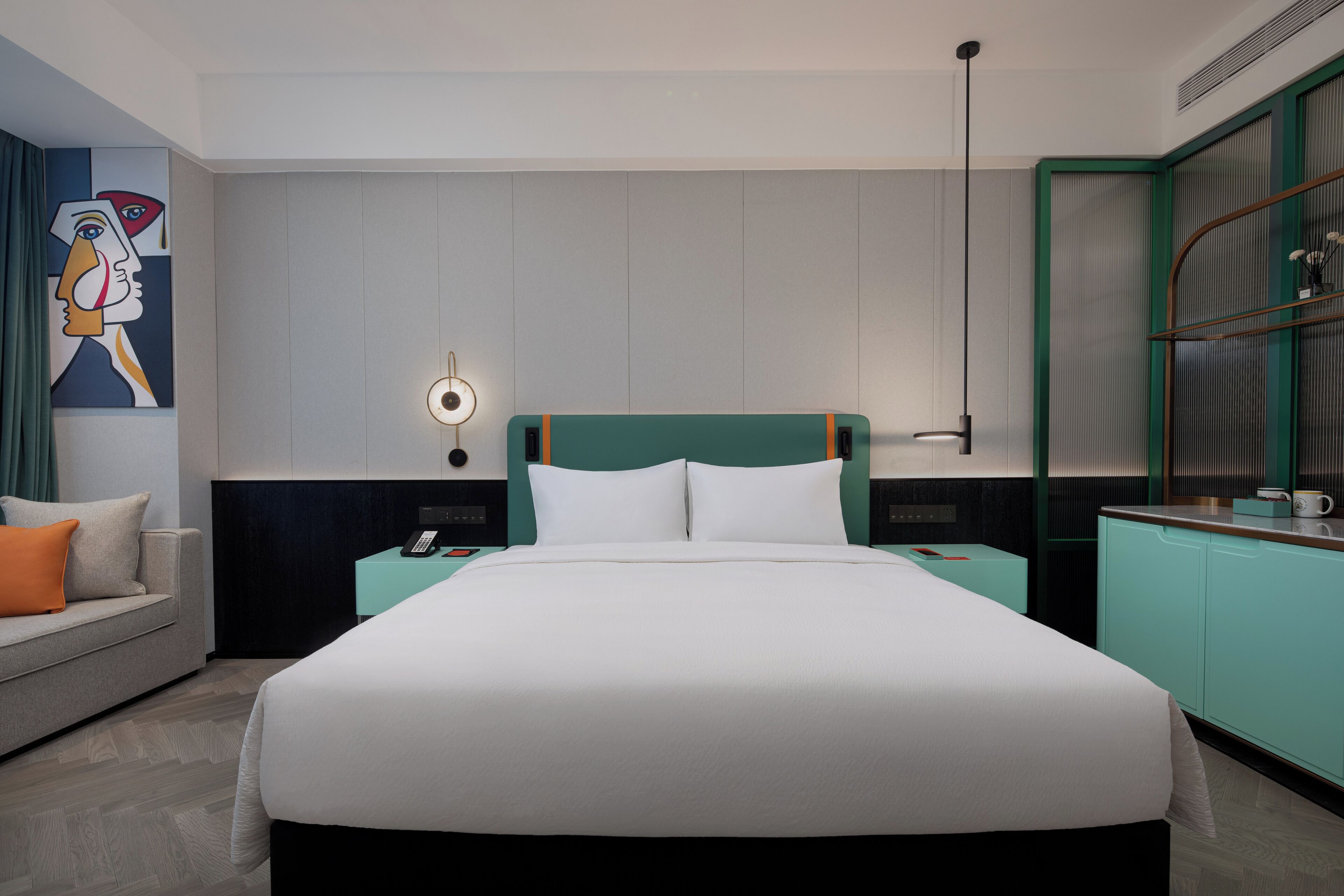 Quarto de hotel moderno com uma cama grande, uma escrivaninha e uma área de estar.