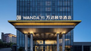 Ein moderner Hotel Eingang mit Glasfassade und einem Schild mit der Aufschrift 'WANDA YI'.