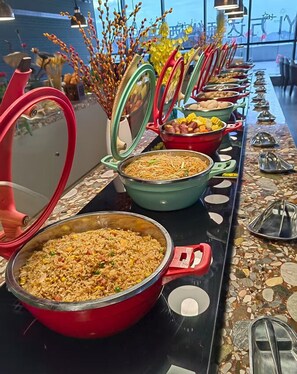 A buffet setup with various dishes in colorful pots and bowls, arranged on a table with a mosaic tile design. - Wanda Yi Yangxin (Huangshi)