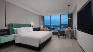 Ein modernes Hotelzimmer mit einem großen Bett, einem Schreibtisch und Blick auf die Stadt.
