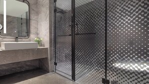 Ein modernes Badezimmer mit Duschkabine aus Glas, Marmorwaschbecken und Spiegel.
