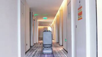 Un pasillo de hotel con un ascensor automático, puertas a ambos lados y piso estampado.