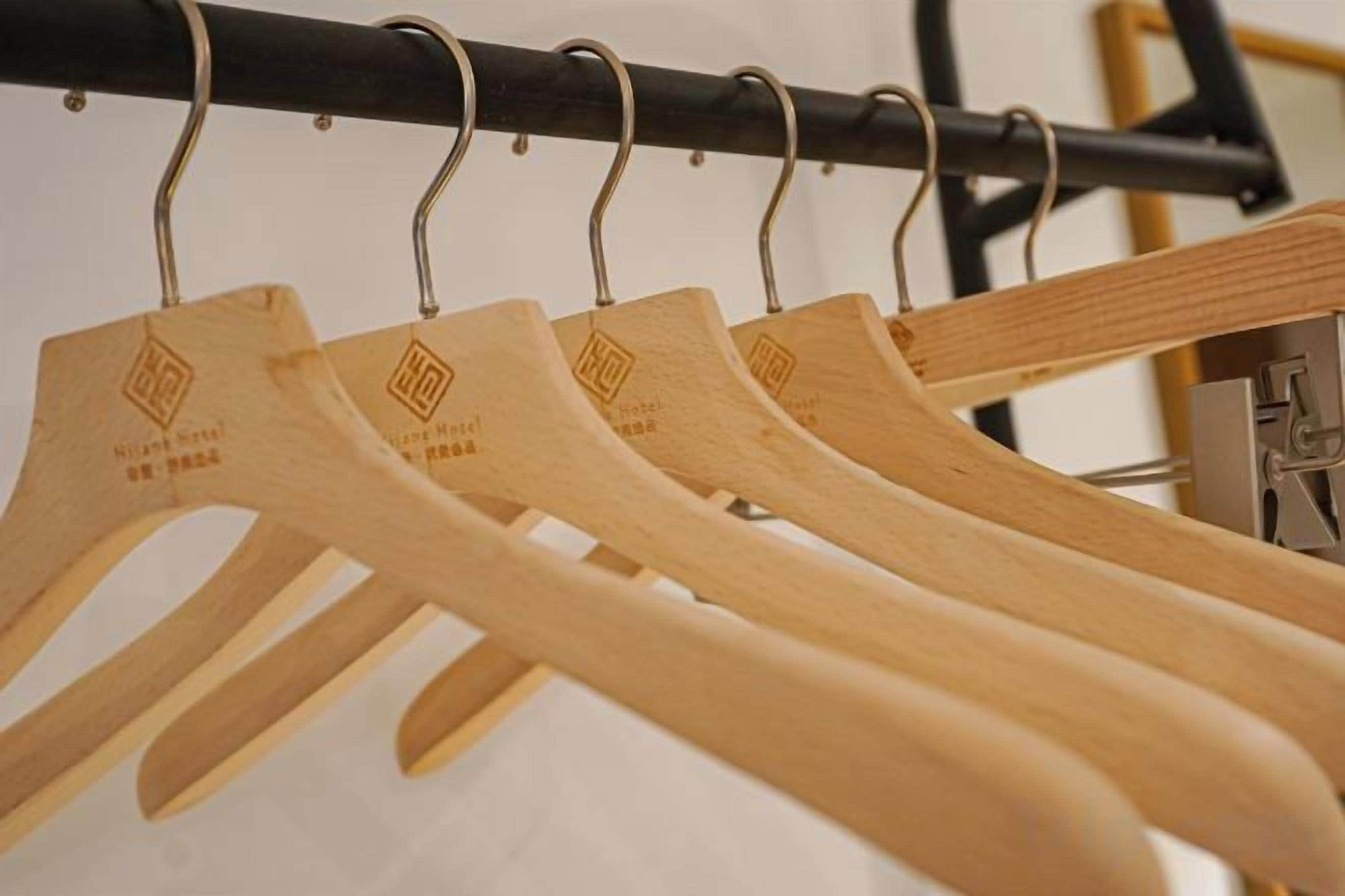 Des cintres en bois ornés des logos d’hôtels, disposés sur un portant.
