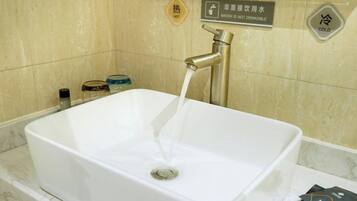 Un baño con un lavamanos blanco, un grifo y un letrero que indica un regulador de temperatura del agua.