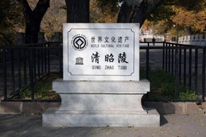 A stone monument with inscriptions, surrounded by a black metal fence and trees in the background. - Chonpines Hotel (Shengyang Provincial Government, Changjiang North Street, Beilin) (Shenyang)