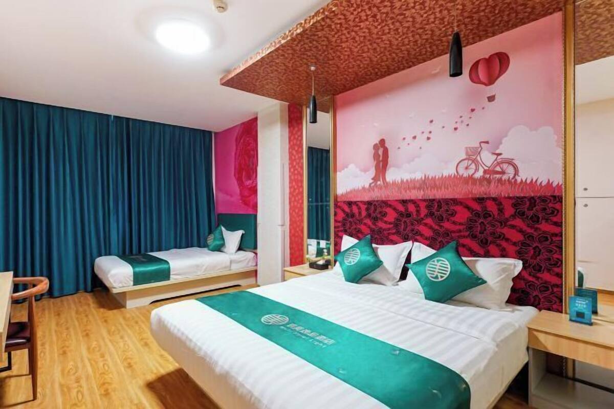 A hotel room with two beds, a desk, and a mirror.