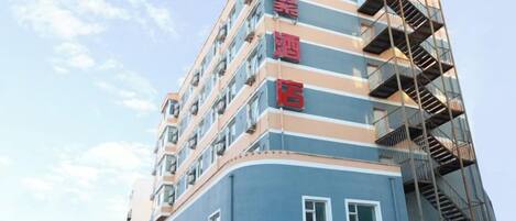 A multi-story hotel building with a blue facade and red signage.